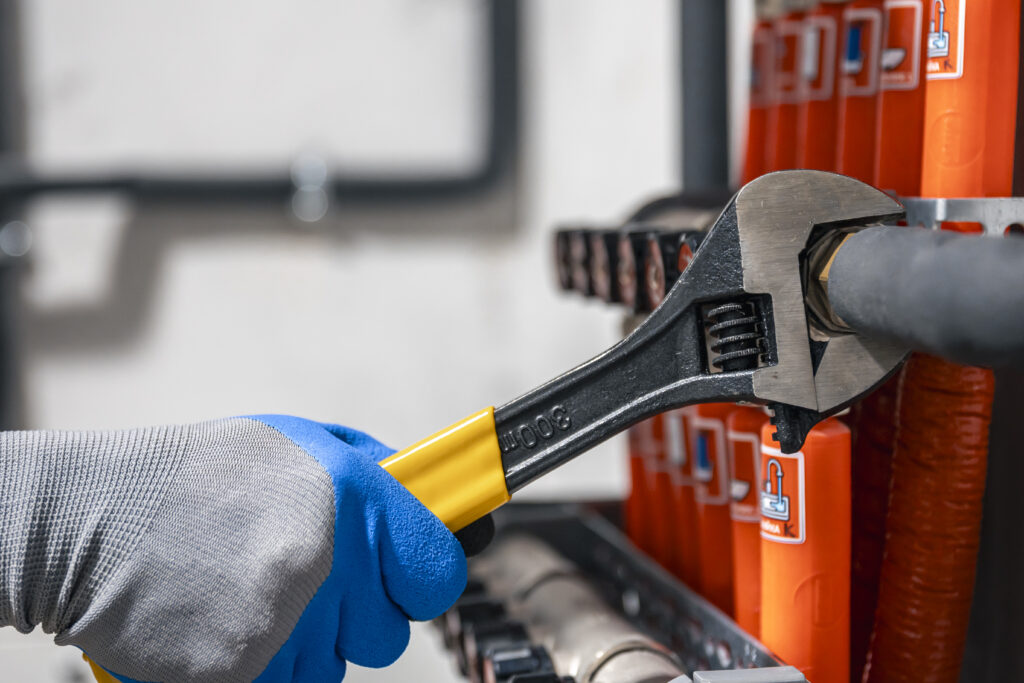 Male hands with a wrench turning off valves.