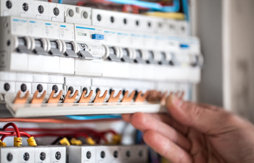 man-electrical-technician-working-switchboard-with-fuses-installation-connection-electrical-equipment-close-up